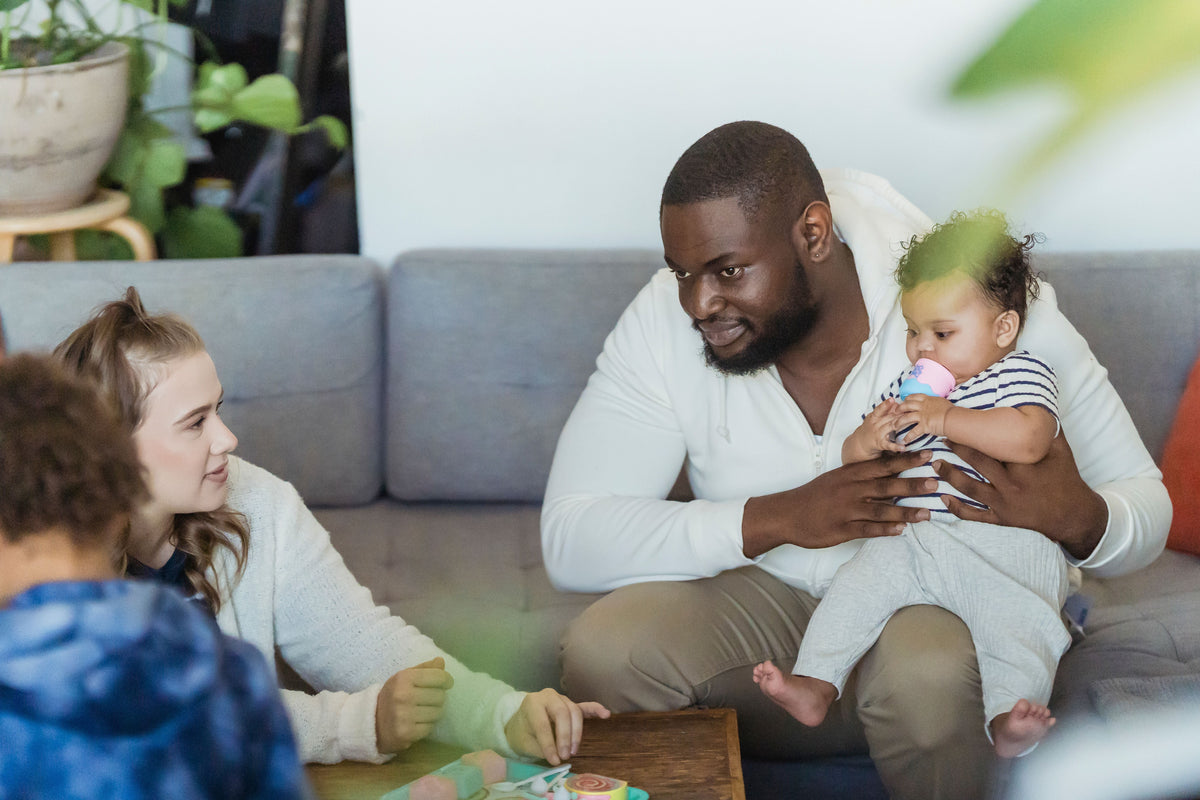 Siblings and family talking together on a sofa at home