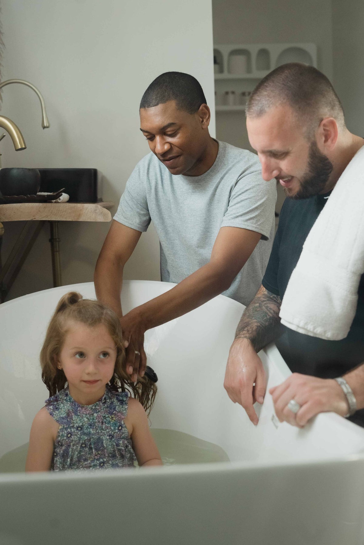 Parent helping a child with a hair-washing routine in the bathroom