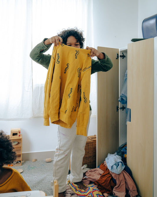 Young person choosing clothes from a wardrobe in a bedroom