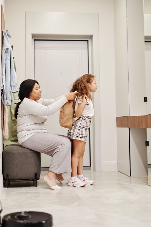 Child with a backpack preparing for school with a parent